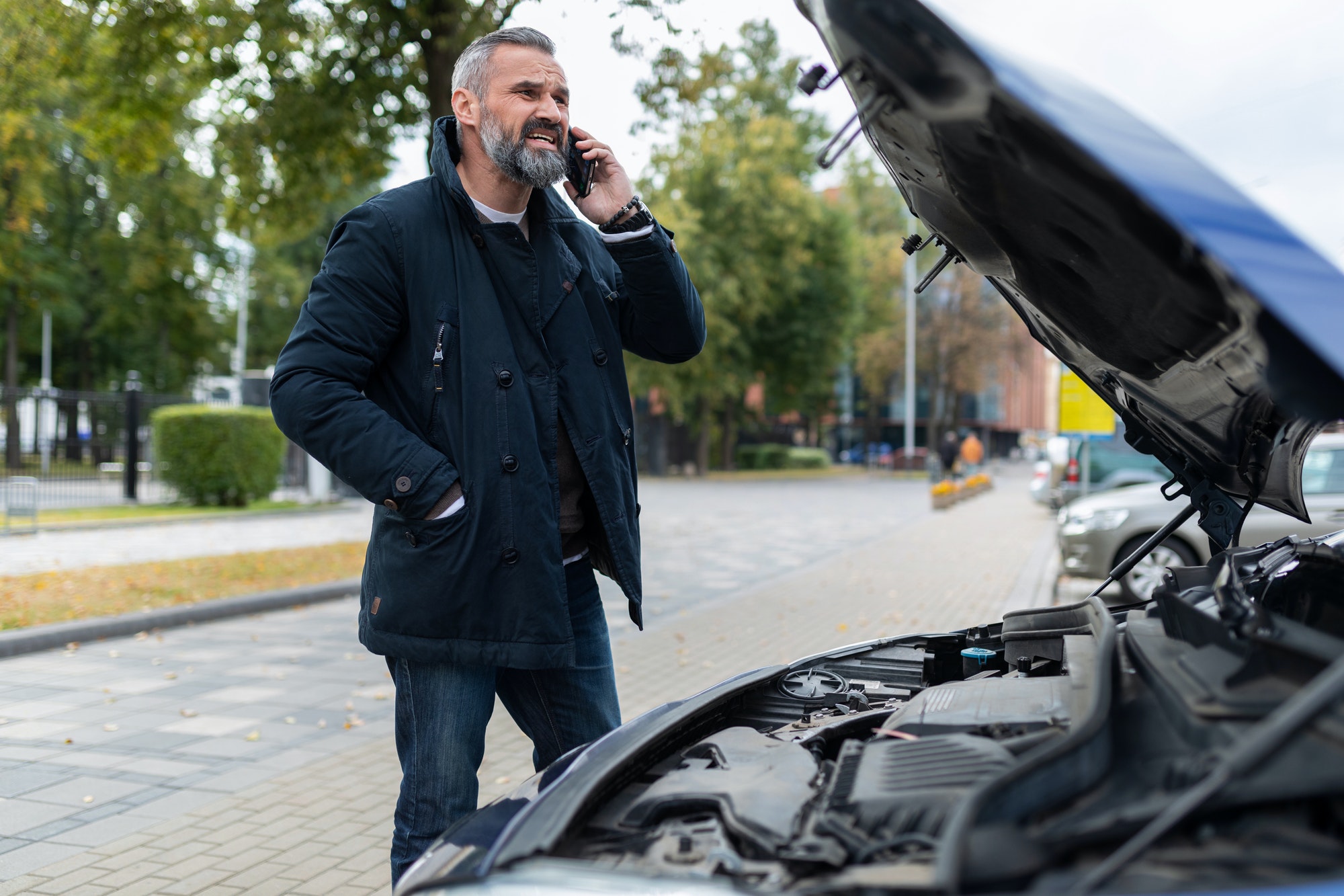 Types Of Tow Trucks - A Comprehensive Guide a man calls a tow truck next to a broken car in the city