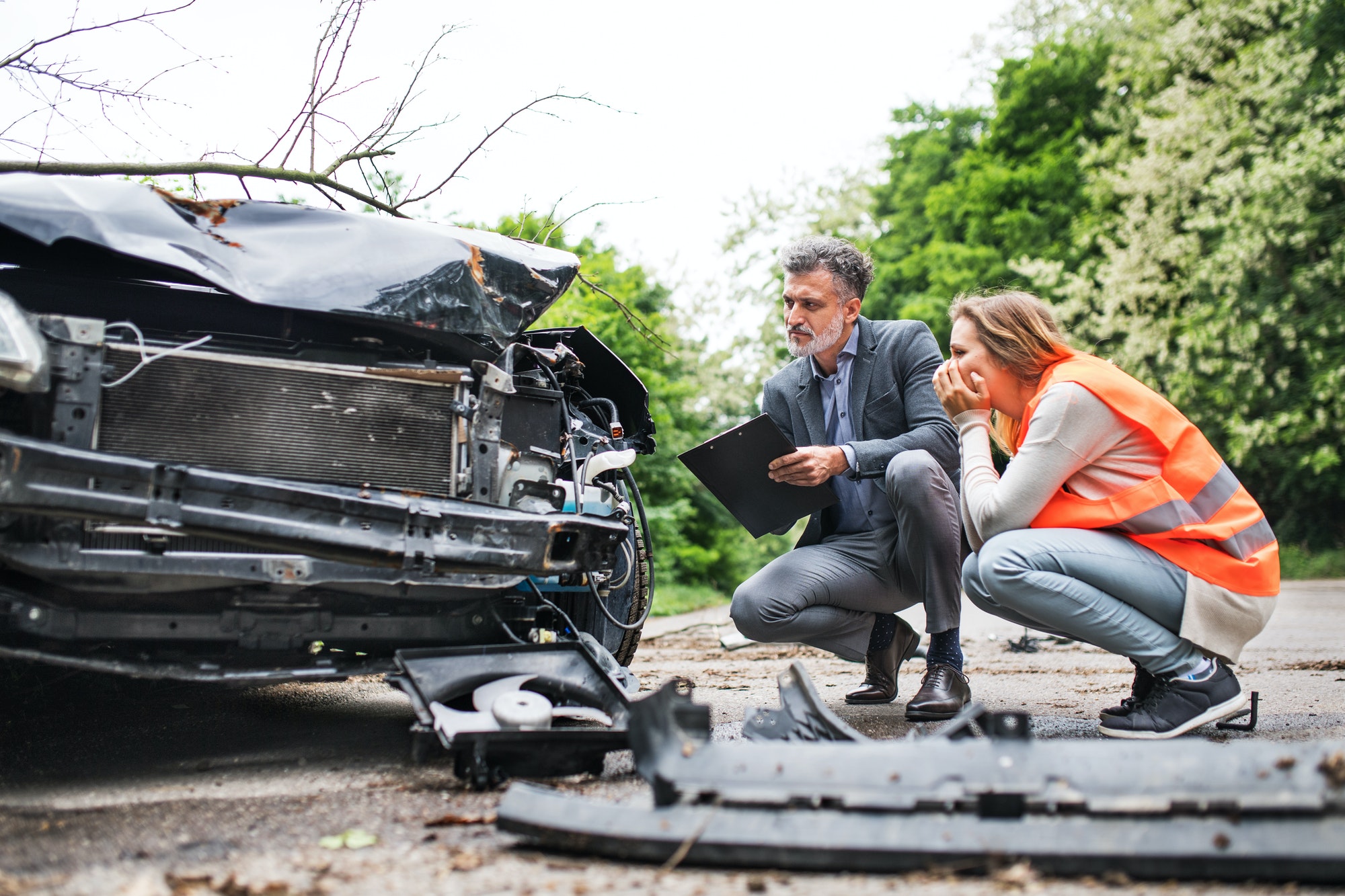 The Value of Community Towing Services in Minnesota, USA An insurance agent and a woman driver looking at the car on the road after an accident.