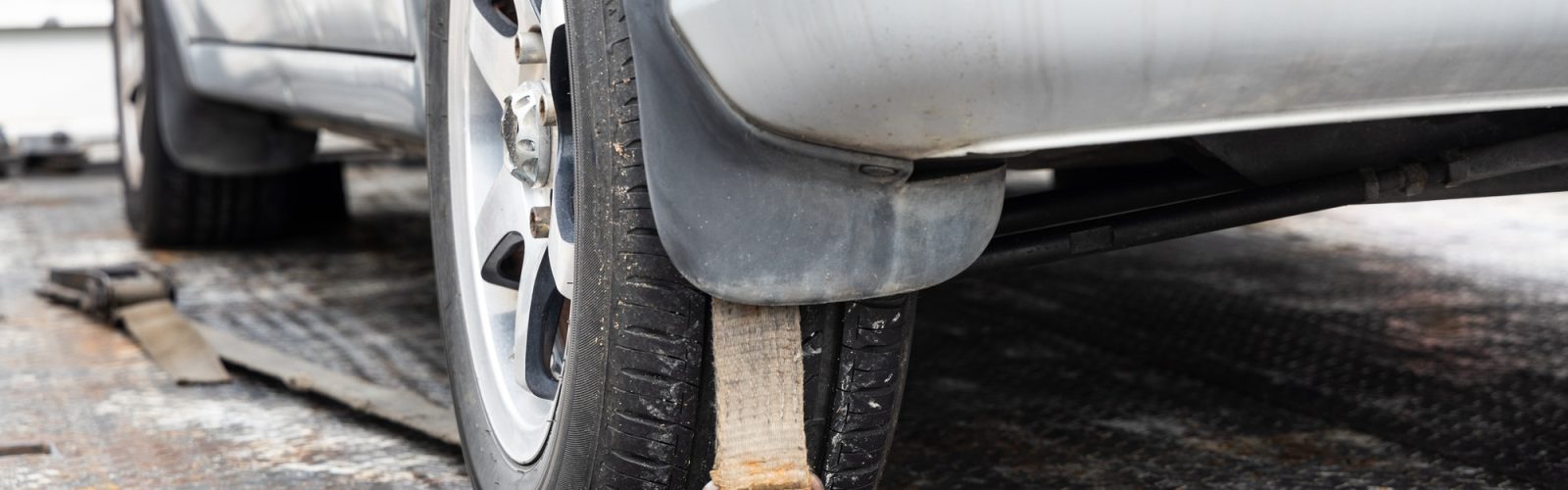 Navigating Emergencies: Unveiling the Fastest Roadside Assistance Near Me Close-up of car wheel tied with safety harness on flatbed tow truck