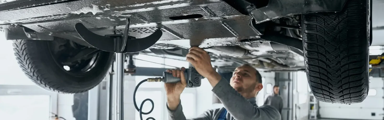 Car Suspension Repair Cost - What to Expect?Competent mechanic in blue overalls repairing car suspension